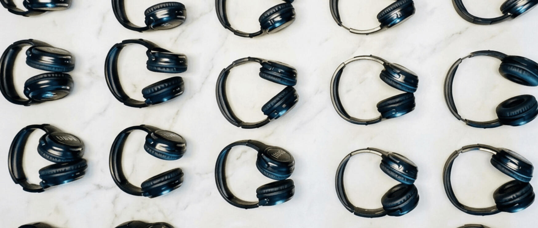 Birdseye image of Flow Silent Disco headphones laying in unison on white marble